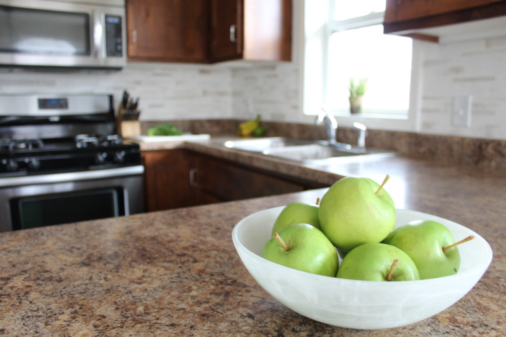 Accessorize your kitchen counters with few colorful accessories to set off wood cabinetry and the clean white backsplash.