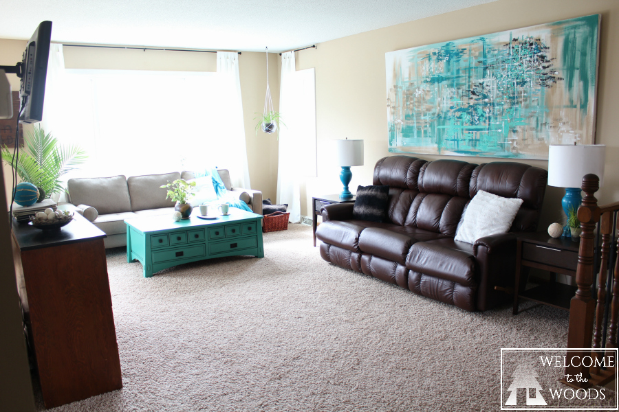 Living room makeover with gorgeous large wall painting, bright turquoise and teal accents, mismatched couches, and an eclectic modern aesthetic.