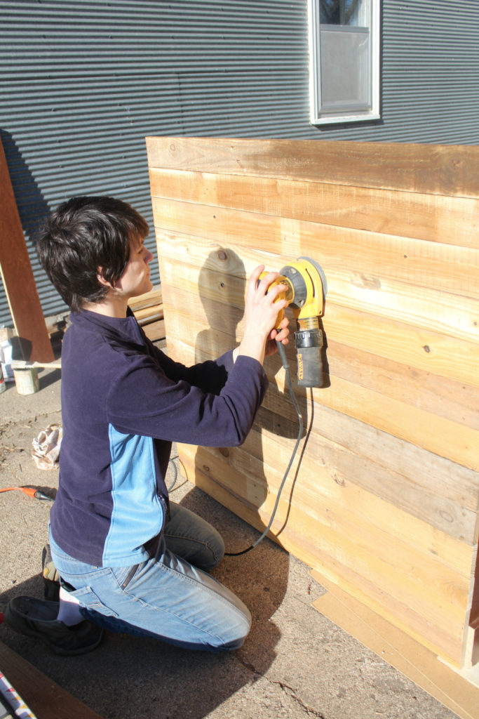 Sanding down reclaimed wood to stain it.